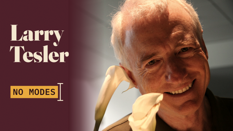Larry Tesler mỉm cười trong ảnh chụp năm 2007, bên mảng nền màu đỏ đô có tên ông và một nhãn tô sáng ghi No Modes cạnh con trỏ văn bản.